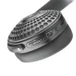 Close-up of a black wireless Bluetooth speaker with a perforated metal grille and side controls, including power and volume buttons.