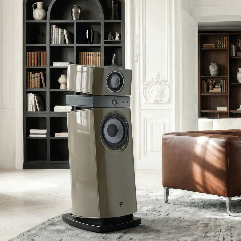 Tall beige floor-standing speaker system with multiple components in a stylish living room beside a black bookcase filled with books and decor.